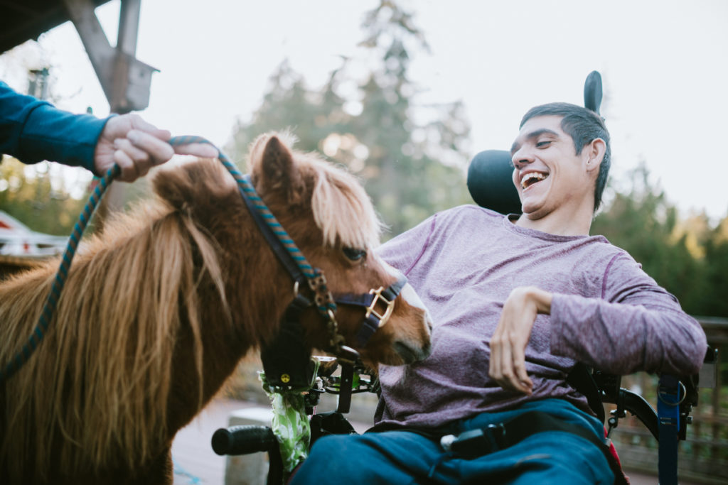 A young man with cerebral palsy is undergoing equestrian therapy.
